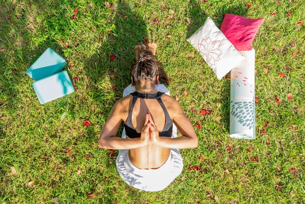 Top View of Young Woman Practicing Yoga on a Green MeadowSitting and Bending Forward