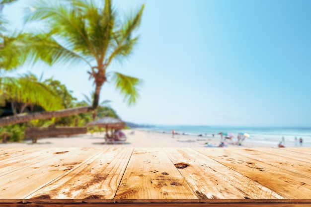 Top of wood table with seascape, palm tree, calm sea and sky at tropical beach