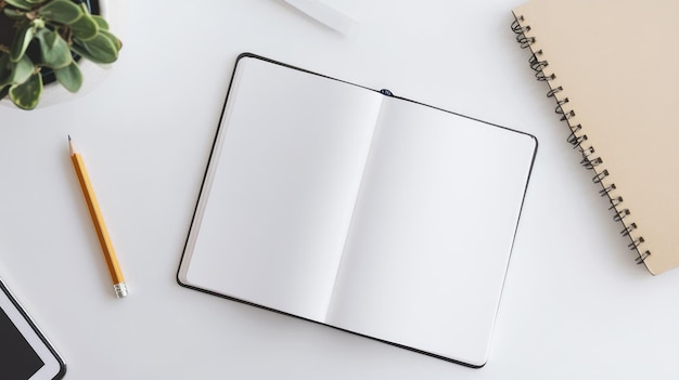 Photo topdown view of an open notebook with a pencil and a potted plant on a white desk showcasing a neat and aesthetically pleasing workspace