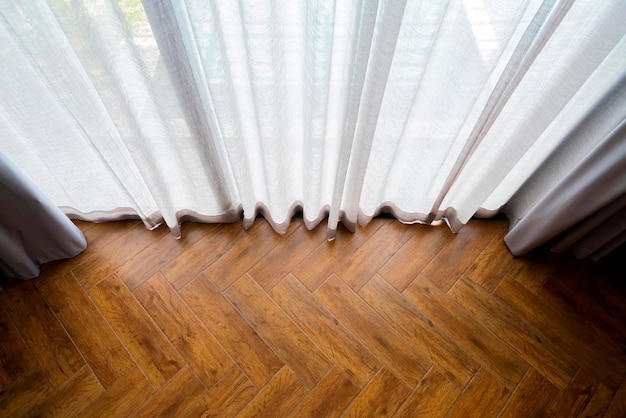 Topview of white sheer curtain with pattern of natural wood floor morning sunlight through big window glass interior design detailhome interior with light coming form window morning day light at home