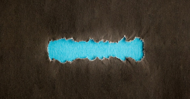 Torn black hole on blue paper background