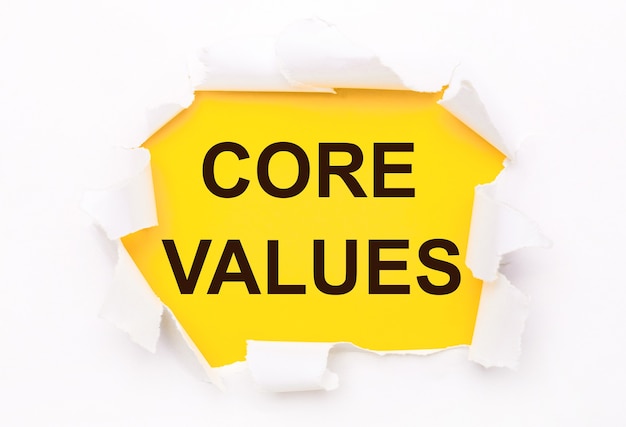 Torn white paper lies on a bright yellow background with the text CORE VALUES