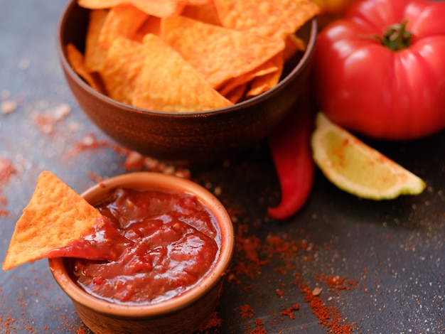 Tortilla nacho chips in a bowl. delicious beer chaser. best food for quick snack. triangular crunchy slice dipped in salsa tomato sauce