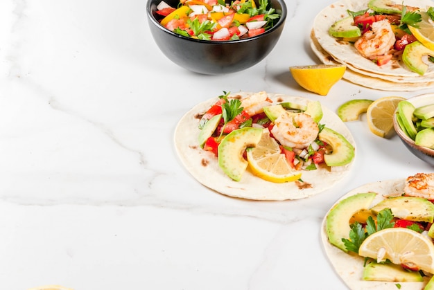 Tortilla tacos with traditional homemade salad, parsley, fresh lemon, avocado and grilled shrimps