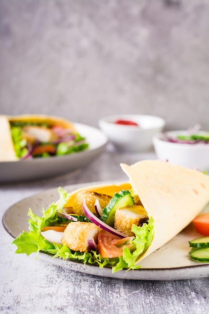 Tortilla wrap with cucumber chicken and tomato on a plate Mexican cuisine Vertical view