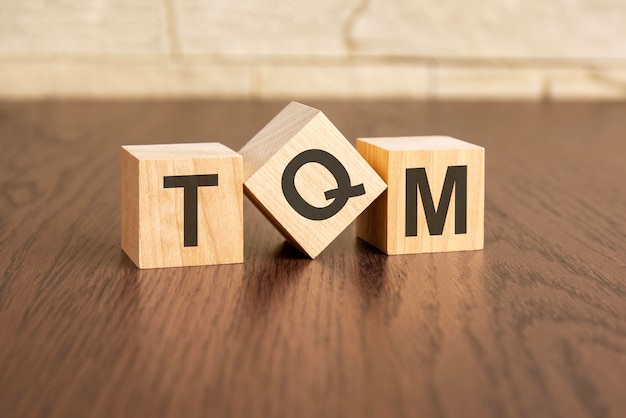 Total quality management concept with symbols TQM on wooden cubes