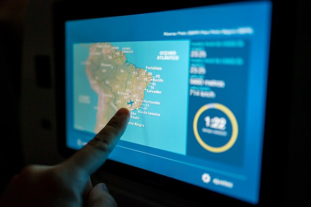 Touch screen, close up of a man pointing finger to LCD screen monitor behind passenger seat on the airplane