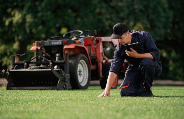 Touching the grass Man is with utility tractor with grass cutter and aerator equipment on the field