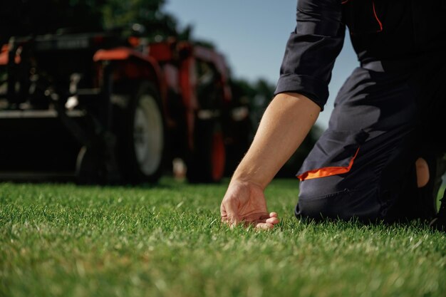 Photo touching the grass man is with utility tractor with grass cutter and aerator equipment on the field