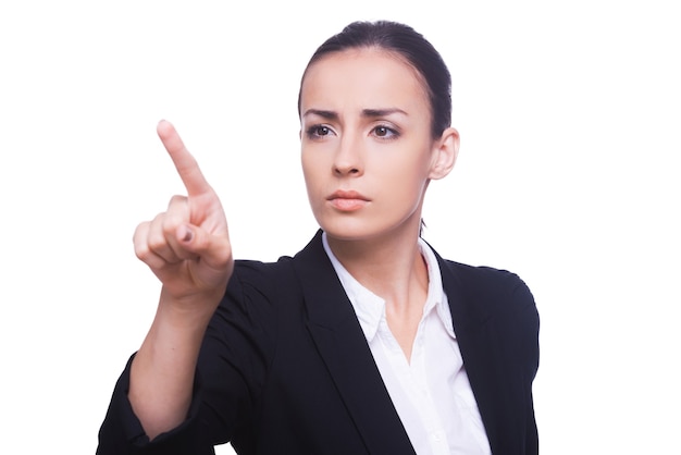 Touching a transparent wipe board. Confident young woman in formalwear touching a transparent wipe board while standing isolated on white