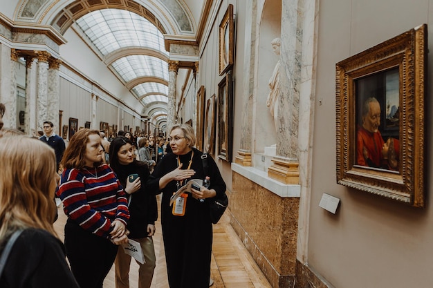 tour guide woman tours a small group of young people in the hallways of the Louvre tells stories