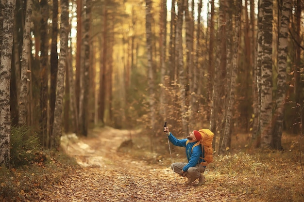 Photo tourist in the autumn forest on a forest road, an adventure in the october forest, one man autumn landscape hiking