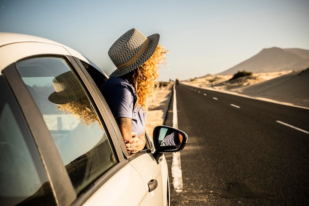 Tourist enjoy sun and outdoors outside the window of the car during a break Vehicle parking on the side of the road and woman people admiring landscape Concept of travel and summer holiday vacation