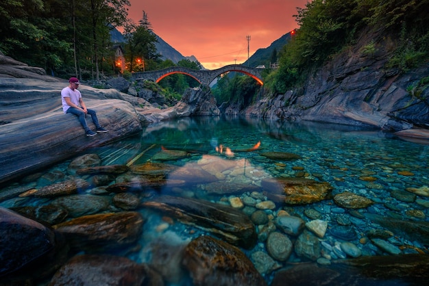 Tourist enjoys sunset at a river near stone bridge in lavertezzo switzerland