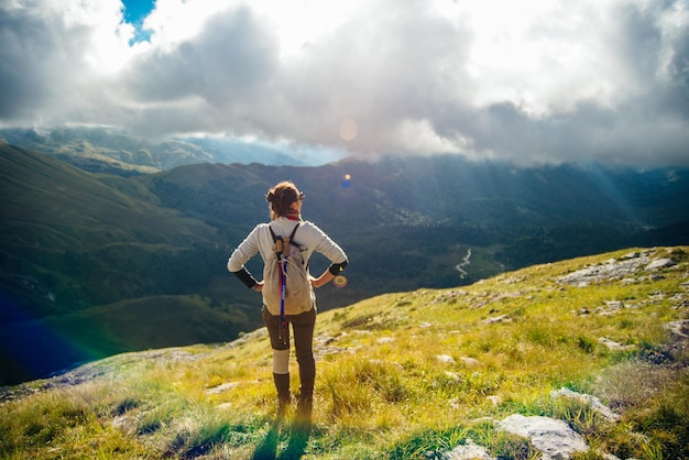 Tourist girl on the hike on the rock in High mountains and enjoying the magnificient view of the valley High quality photo