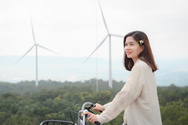 Tourist girl Visit the windmill fields at the renewable power station The background is a wind turbine generating electricity on a beautiful mountain