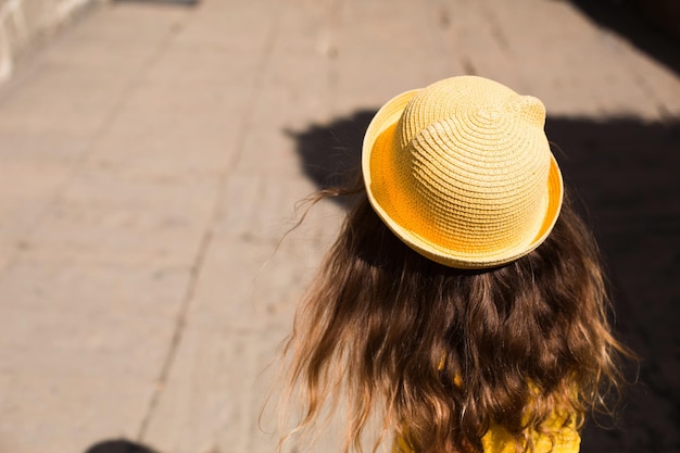 A tourist girl in a yellow hat and sundress walks along the street of the old town made of stone with a fortress Sightseeing tour The child got lost searching for parents