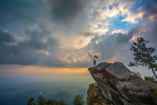 A tourist is looking at a Thai flag on a hilltop in Thailand