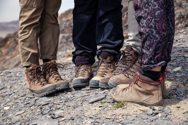 Tourist legs together in brown trekking hiking boots with laces on rocky cliff