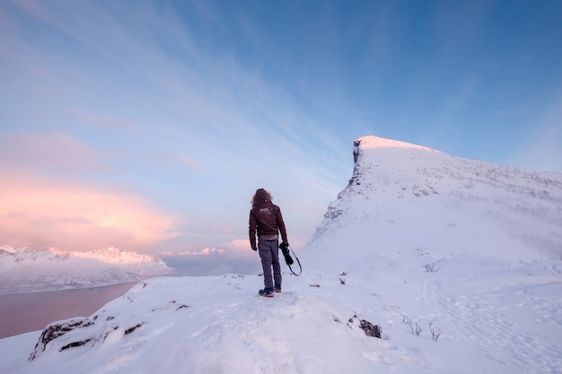 Tourist man climbs on top snowy mountain