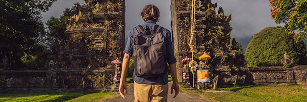 Tourist man walking through traditional balinese hindu gate candi bentar close to bedugul bratan