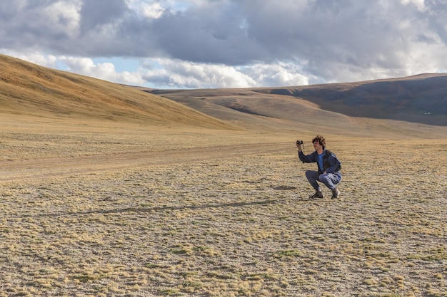 Tourist photographer taking picture of the hills with mountains in Mongolian Altai