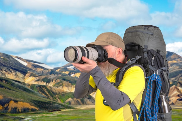 tourist photographer with a backpack photographs the beauty of nature in the mountains