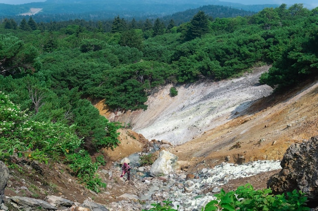 Tourist photographs a geothermal mineralized stream on the slope of the Mendeleev volcano Kunashir island