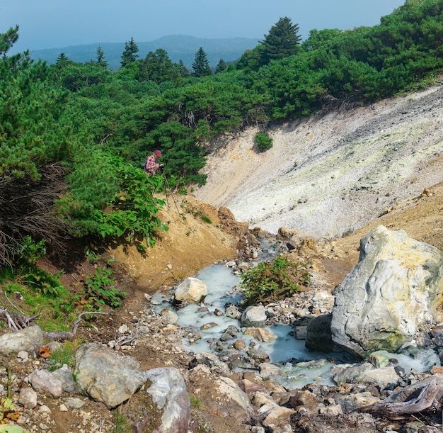 Tourist photographs a geothermal mineralized stream on the slope of the Mendeleev volcano Kunashir island