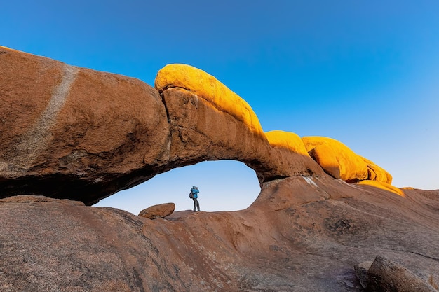 A tourist photographs a picturesque stone arch in the Spitzkoppe area Namibia