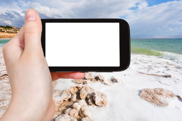 Tourist photographs salt coastline of Dead Sea