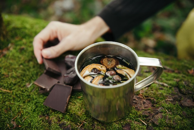 Tourist preparing herbal tea with chocolate while hiking