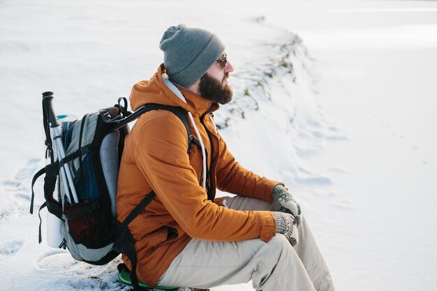 Tourist sits and rests while climbing in winter mountains