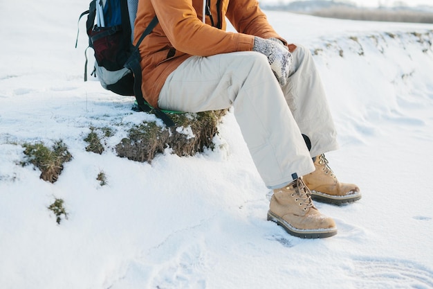 Tourist sits and rests while climbing in winter mountains