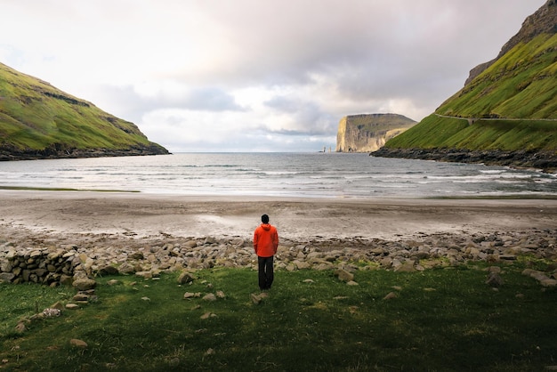 Tourist standing at the beach in tjornuvik in the faroe islands denmark