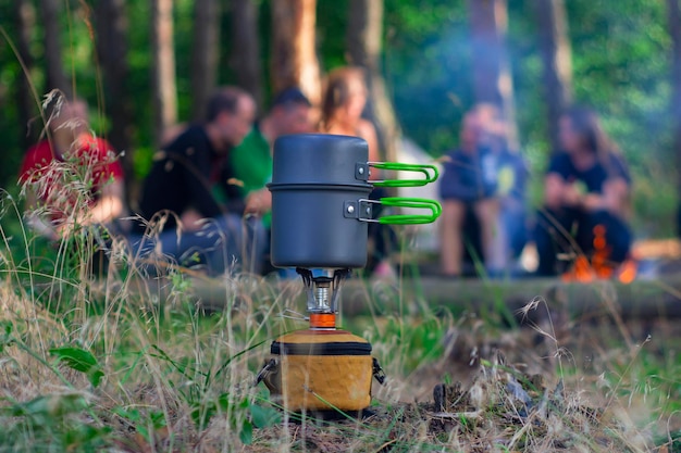 Tourist stove gas for camping and recreation against the backdrop of the forest and vacationing tourists