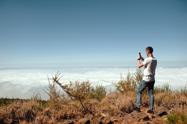 Tourist taking photo of beautiful mountain landscape with mobile phone