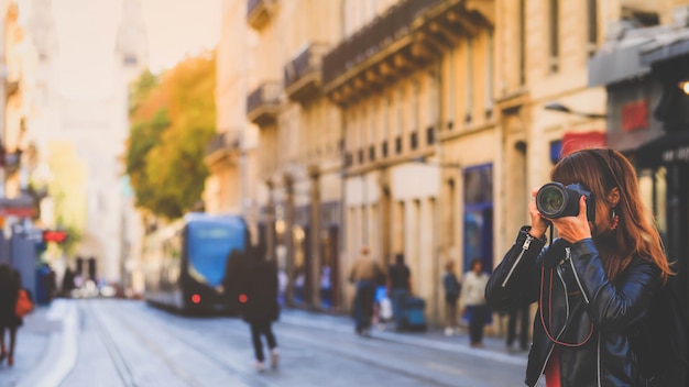 Tourist taking photo on street with tram rails and Saint Andre Cathedral in Bordeaux, France