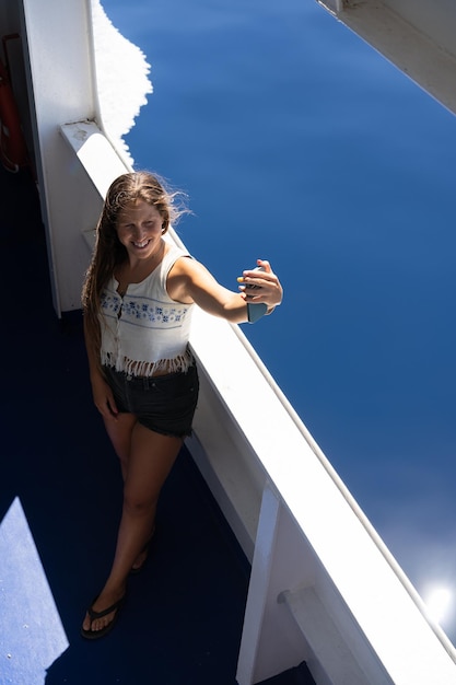 Tourist Taking Selfie with her smartphone smiling in a ferry boat