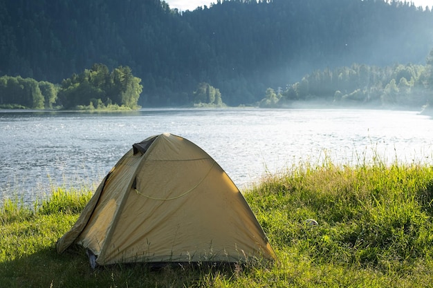 Tourist tent on river bank Camping tent near mountain river Local tourism weekend at nature