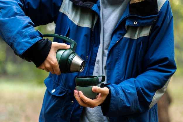 A tourist traveler pour hot water from thermos