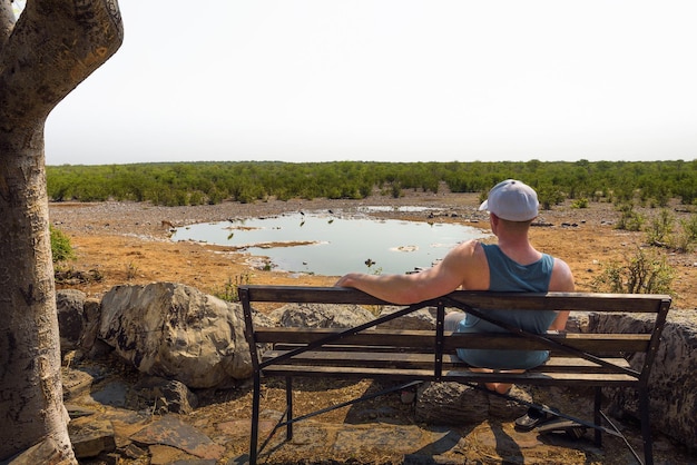 Tourist waits for wildlife at the moringa waterhole near halali etosha namibia