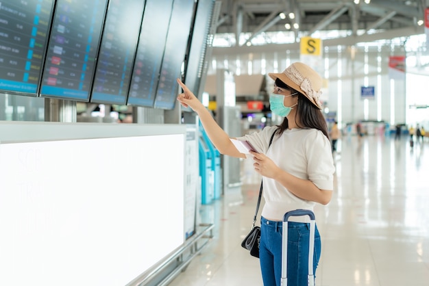 Tourist wearing face mask checking flight from arrival departure board