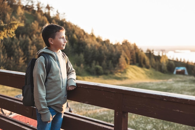 Tourist with backpack enjoying beautiful landscape view Portrait of teenage boy hiker resting in nature Active lifestyle Concept of local travel