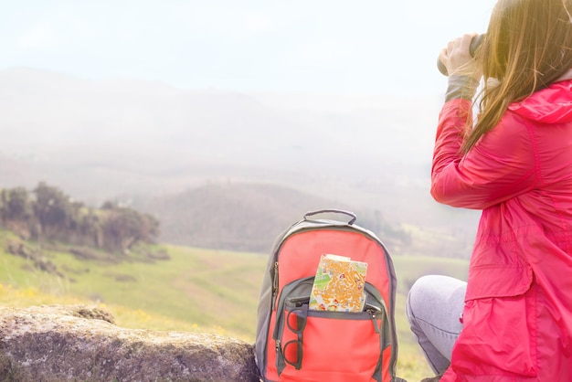 Tourist with binoculars looking at scenic view in mountains