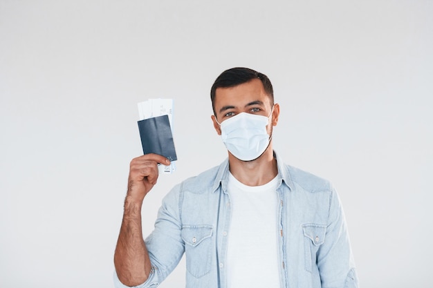 Tourist with ticket Young handsome man standing indoors against white background