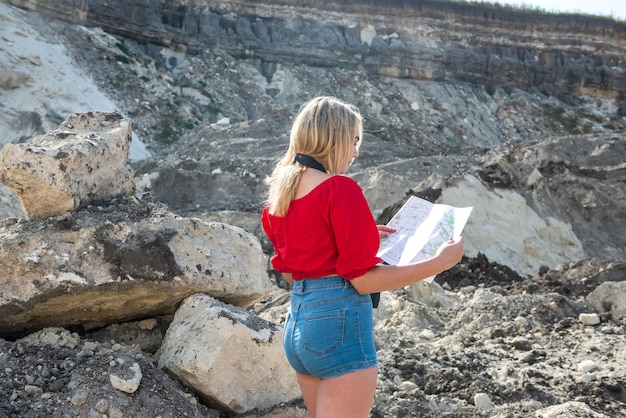 Photo tourist woman look the map among the stones with camera