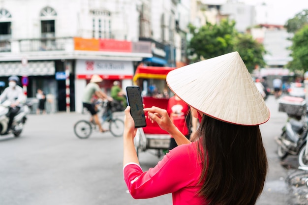 Tourist woman looking at the map in mobile phone while walking sightseeing in Hanoi city Vietnam