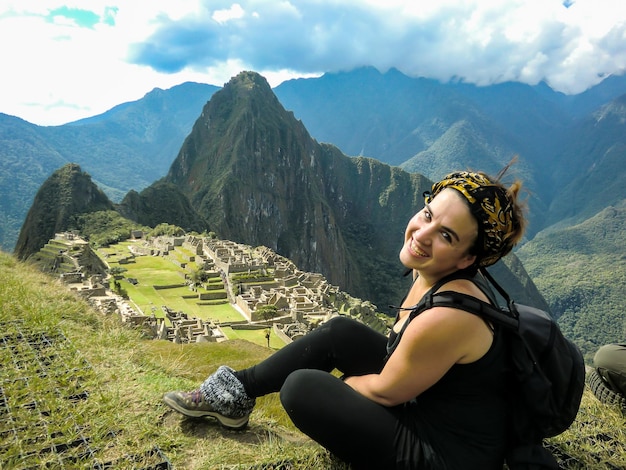 Tourist woman posing in the citadel of Machu Picchu Huayna Picchu mountain in Cusco Peru