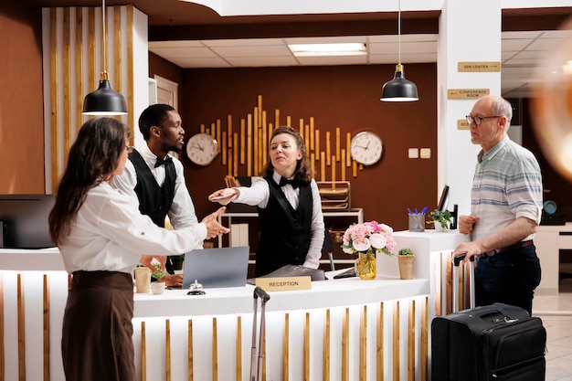 Tourist woman receiving identification documents from concierge after confirmation of reservation. Elderly couple wait at the hotel reception counter where the kind staff assists them with check-in.